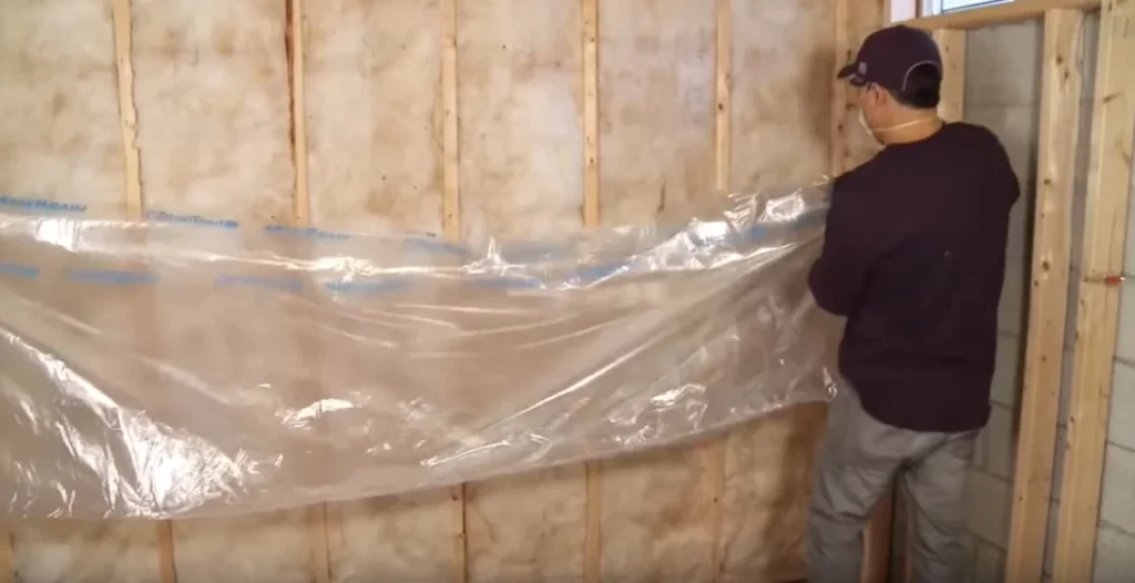 Installation of heavy-duty wall vapor barriers in a Charlotte basement to prevent moisture transmission and mold.